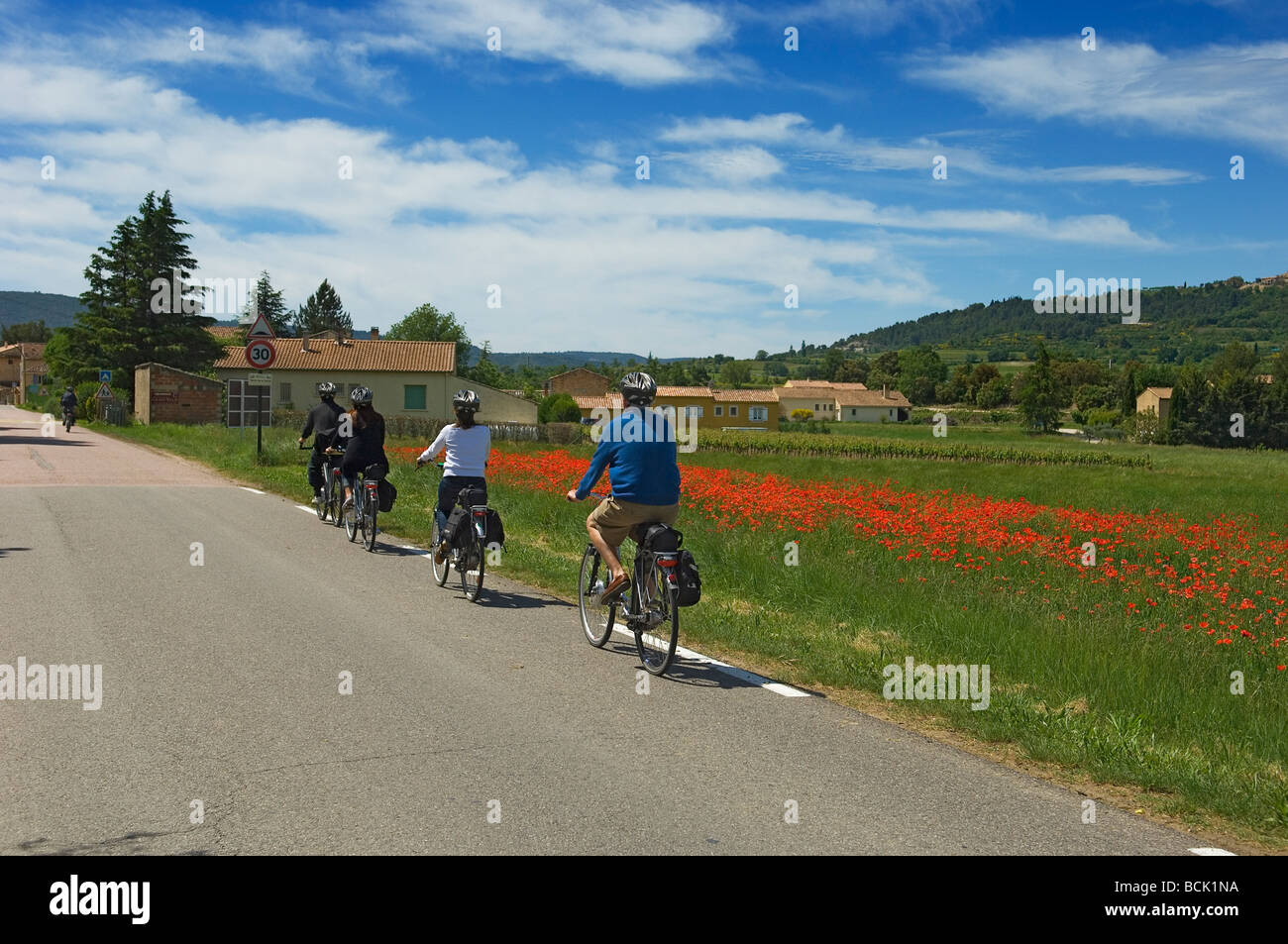 Eine Gruppe von Radfahrern auf Elektro-Fahrräder sind auf die ruhigen Mohn gesäumten Landstraßen der Provence Frankreich Tour Stockfoto