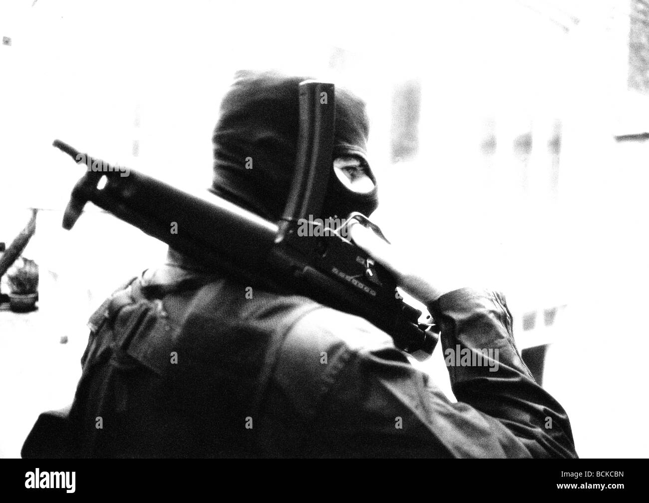 Trägers Ski-Maske Betrieb Maschinengewehr auf der Schulter, b&w Stockfoto
