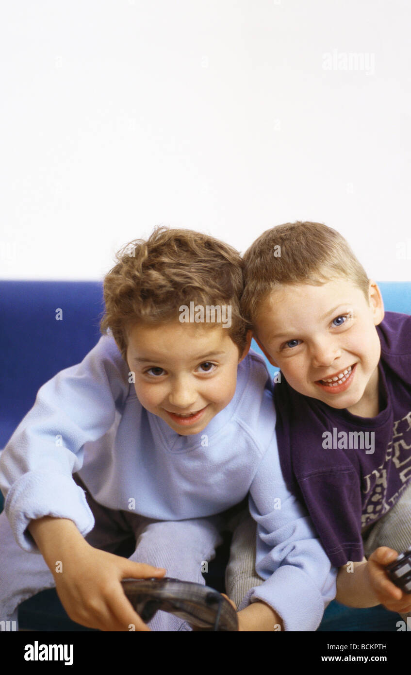 Zwei jungen auf Sofa mit Joysticks, Blick in die Kamera Stockfoto