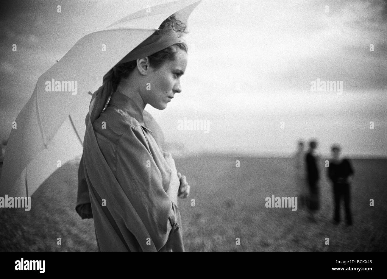 Frau am Strand unter Dach, Gruppe in Ferne, b&w Stockfoto