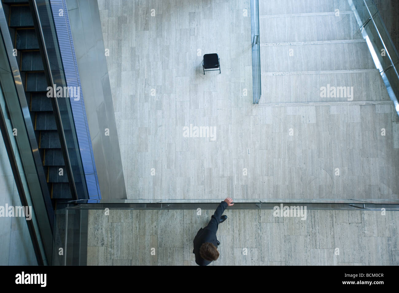 Architektonische Schuss, Mann auf Mezzanine, hält Schiene, Blick vom direkt über Stockfoto