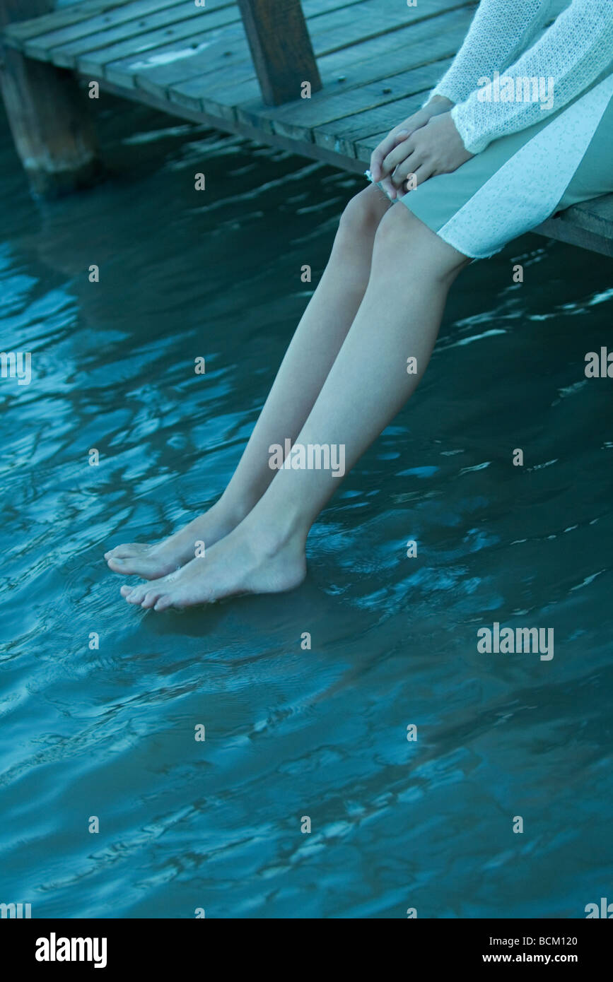 Frau sitzt am Rand des Pier, baumelnden Beinen in Richtung Wasser, niedrigen Abschnitt Stockfoto