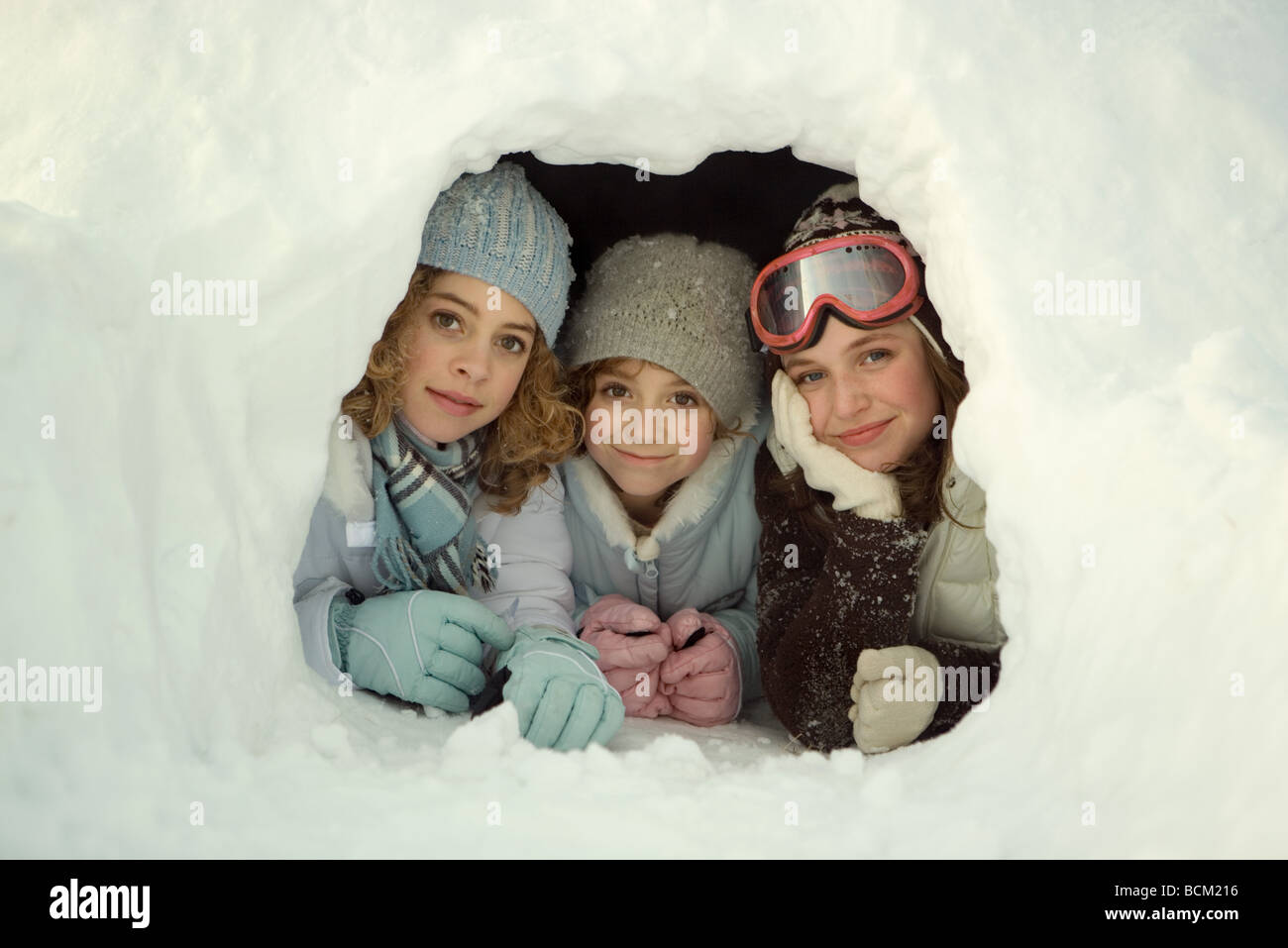 Drei junge Freunde liegen im Schnee-Tunnel, lächelnd in die Kamera Stockfoto