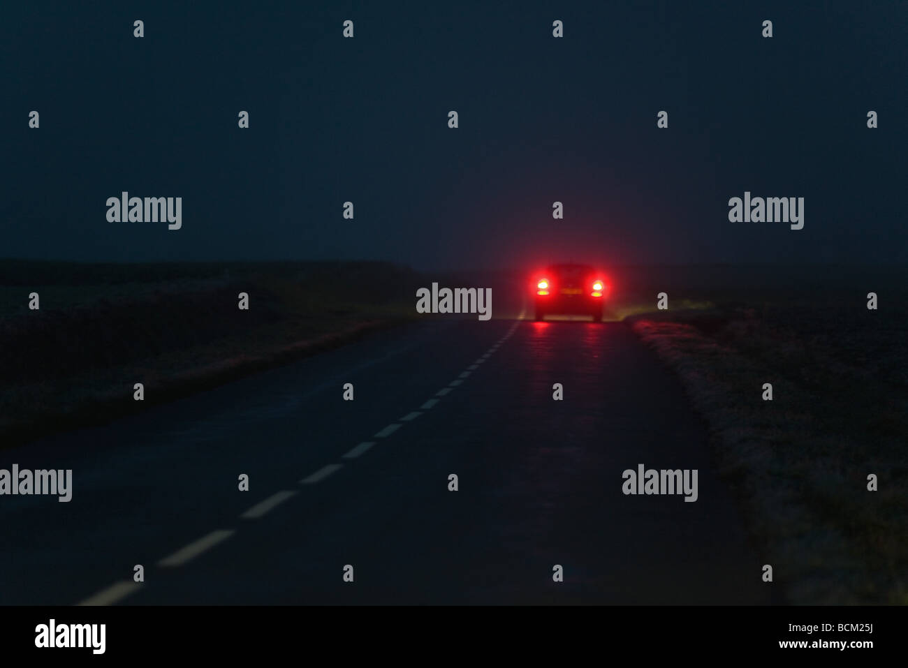 Auto mit leuchtenden Schweif leuchtet auf Straße bei Nacht, Rückansicht Stockfoto