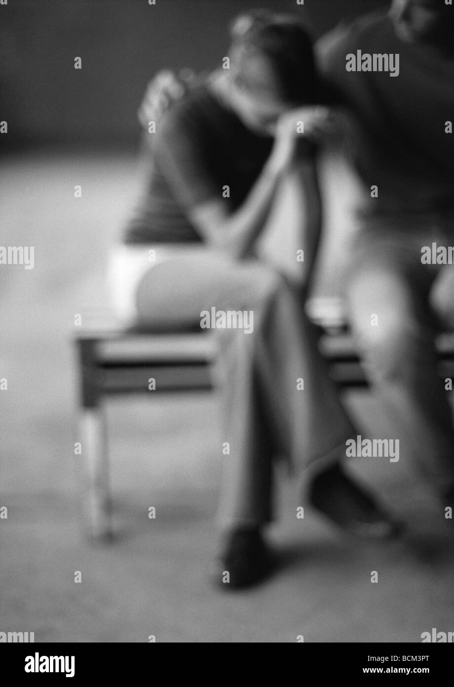 Paar auf Bank sitzend, Frau weinen, unscharf gestellt Stockfoto