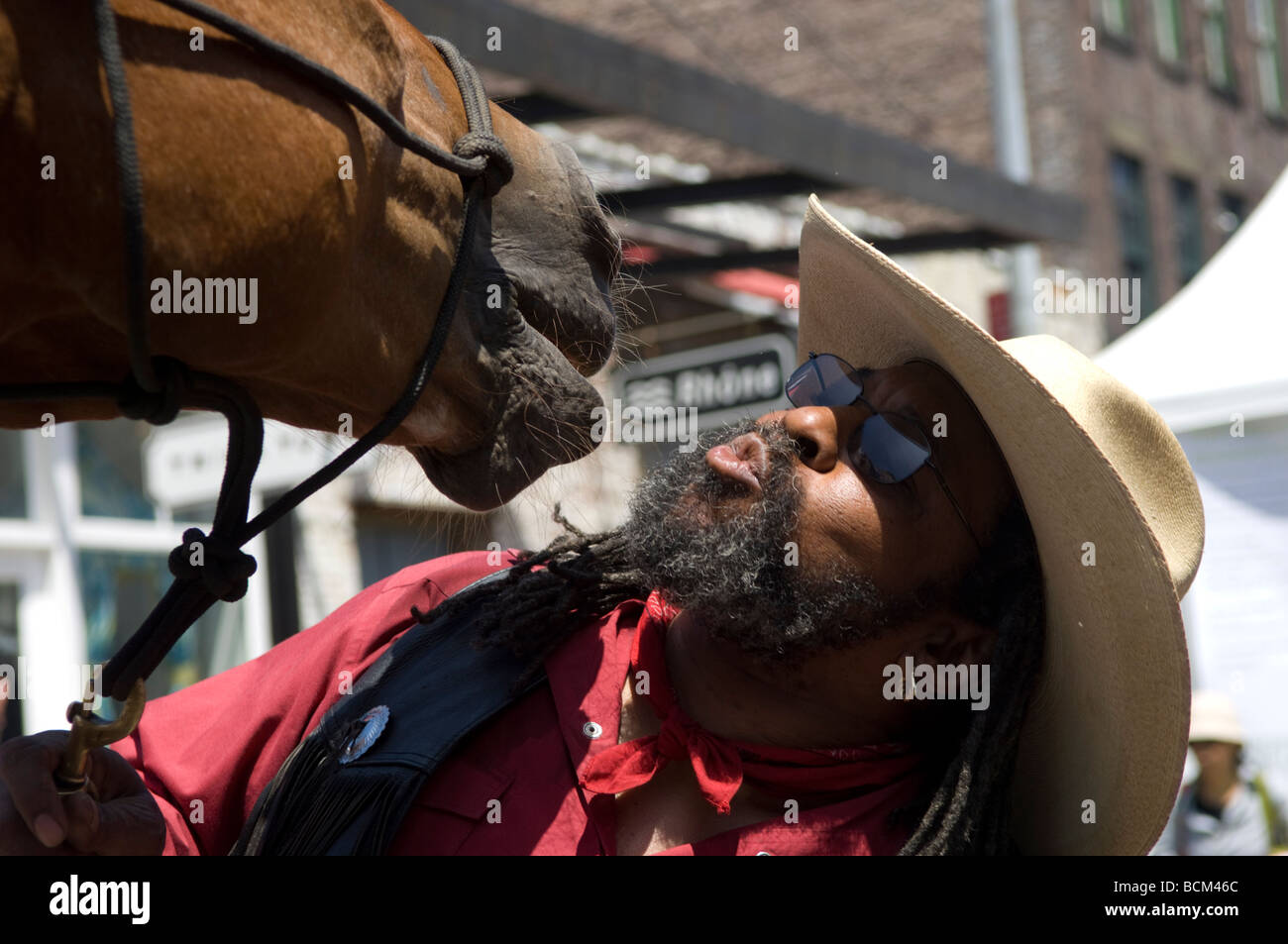 Ein Mitglied der Föderation der schwarzen Cowboys NYC gibt einen Kuss zu seinem Pferd Weide auf der jährlichen Ziel hohe Linie Street Fair Stockfoto