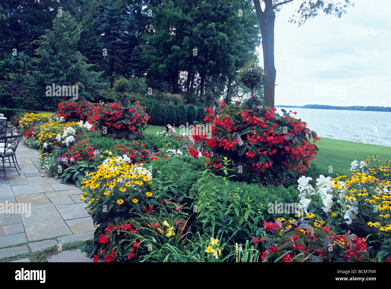 TERRASSE VON MINNESOTA SEE NACH HAUSE IM SOMMER ZURÜCK.  BEGONIEN, LILIEN, RUDBECKIA, TOPIARIES UND ZINNIEN MEHRJÄHRIGE GRENZE. Stockfoto