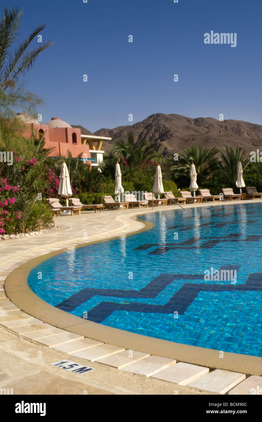 Liegen rund um einen Pool mit den Bergen der Wüste Sinai im Hintergrund Stockfoto