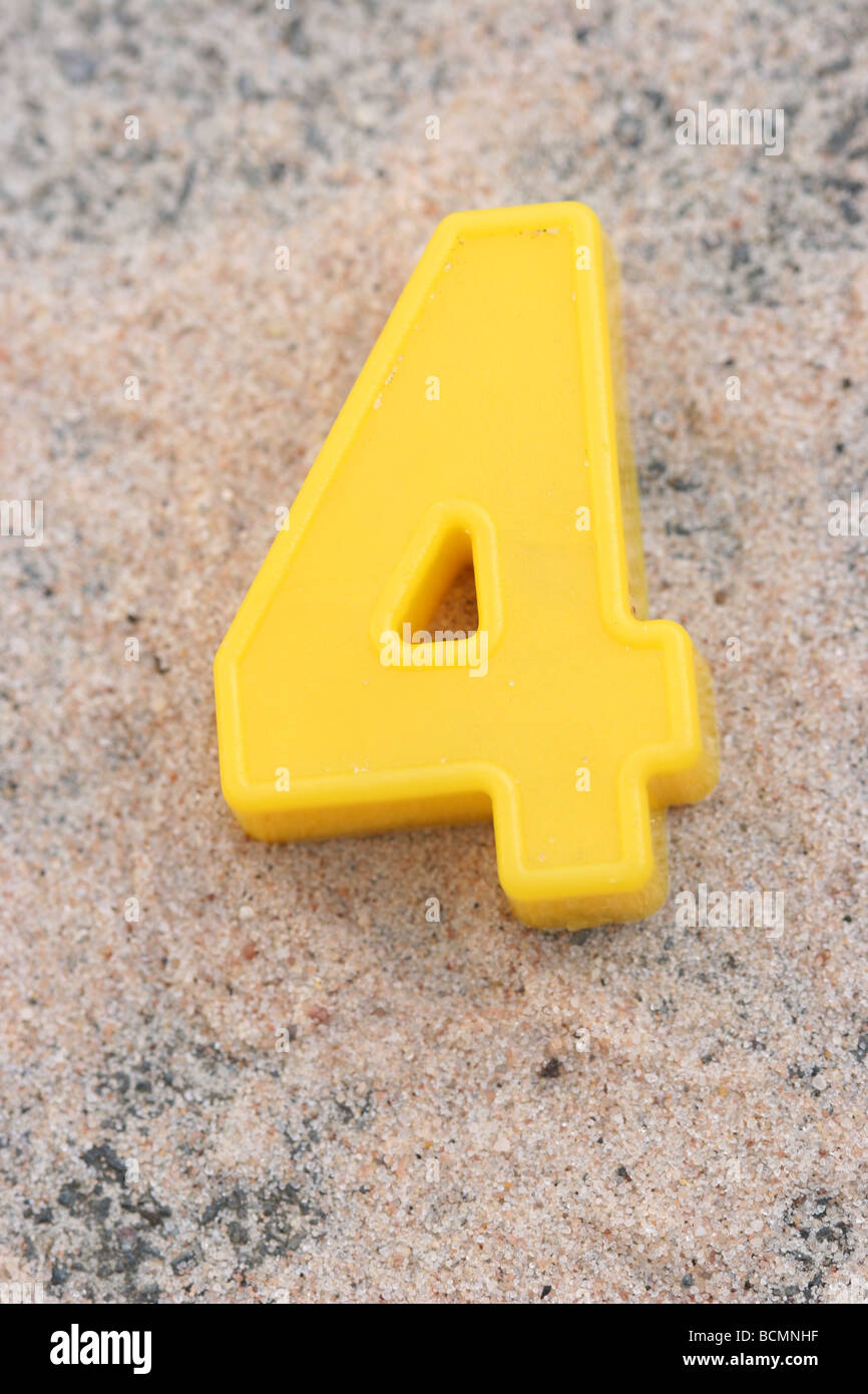 Gelbe Kühlschrank magnet Nummer vier auf Sand Stockfoto