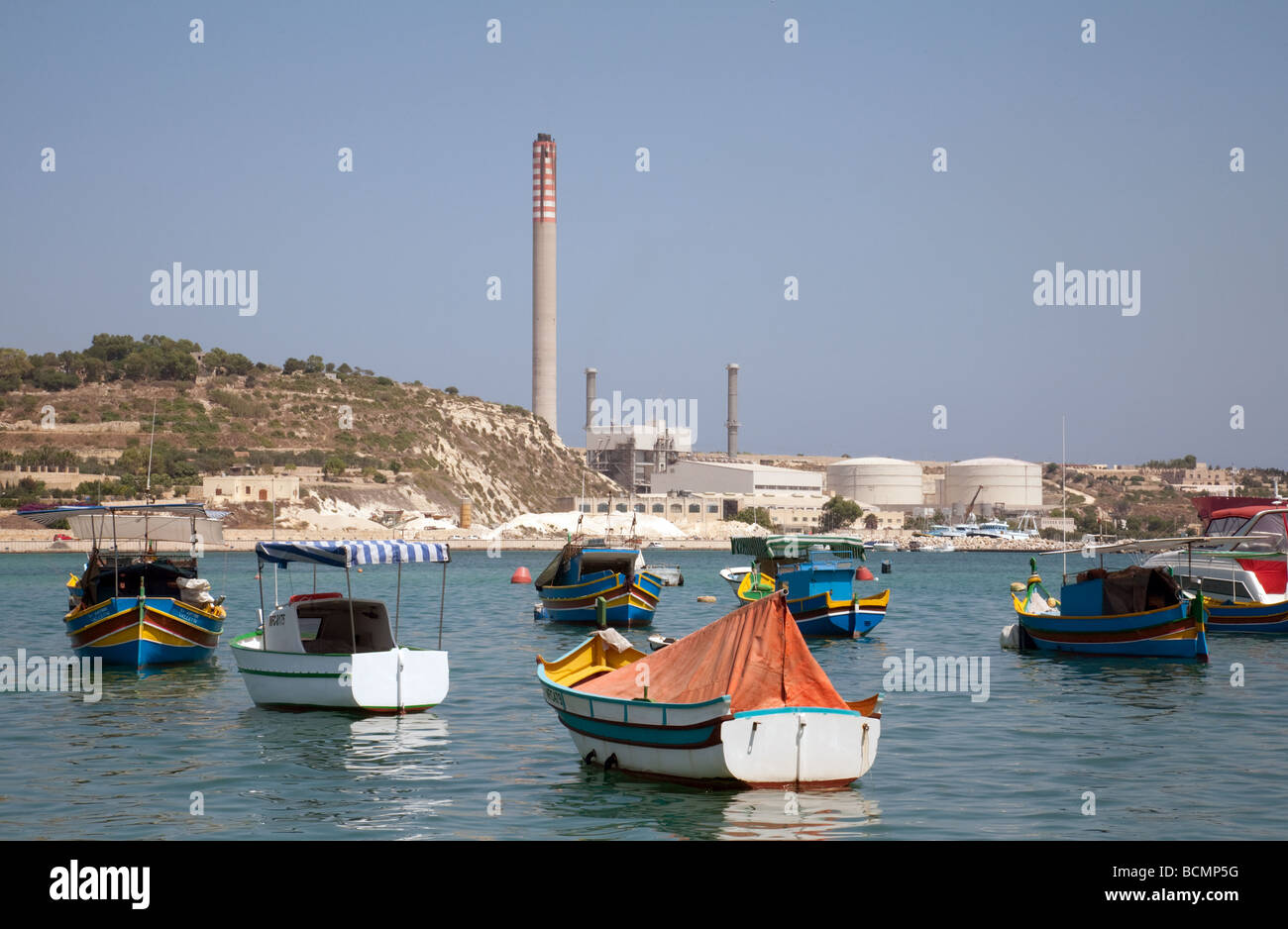 Ruderboote in Marsaxlokk Hafen, liegt Malta mit der schlecht Kraftwerksneubau im Hintergrund Stockfoto