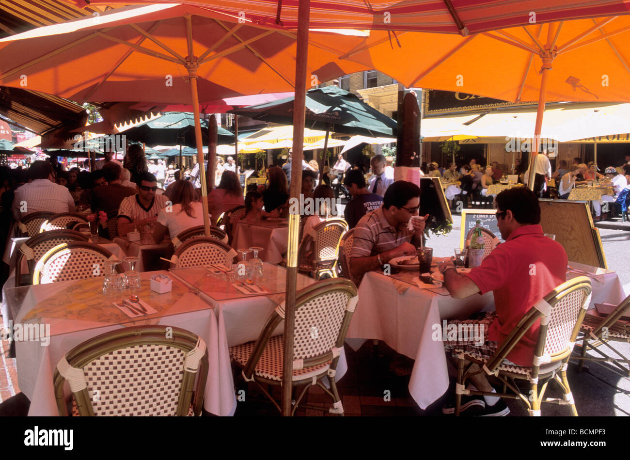 Essen im Freien New York. Menschen, die während einer Hitzewelle im Sommer in einem Café in der Mulberry Street in Lower Manhattan unter Sonnenschirmen sitzen. Little Italy, USA Stockfoto