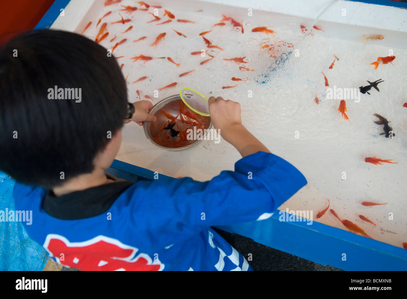 Ein kleiner Junge in der traditionellen Kleidung Fang von Goldfischen auf dem Markt in Tokio Japan Stockfoto