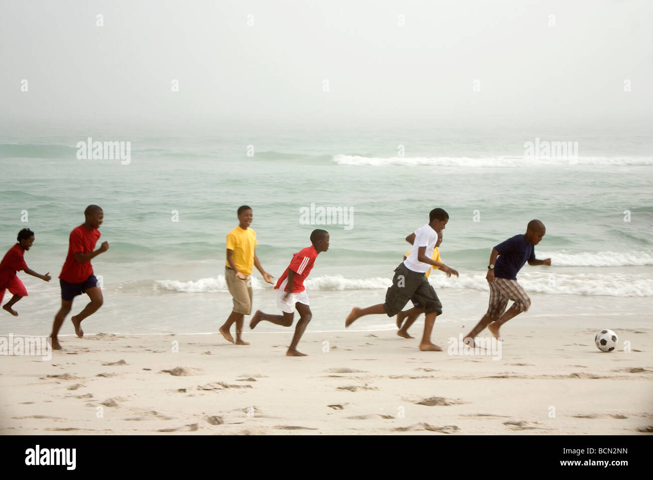 Die Jungs laufen am Strand Fußball zu spielen. Blouberg Beach Stockfoto