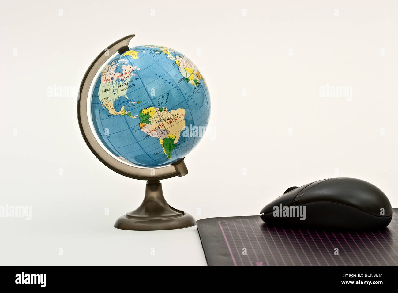 Maus auf eine Maus-Pad in Richtung eines Kunststoff Globus der Welt Stockfoto