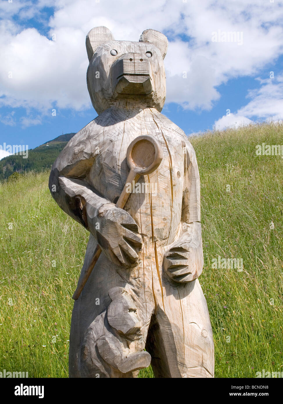 A grob geschnitzt aus Holz Bär ein Jungtier mit einem Holzlöffel durch Fußweg im österreichischen Tirol Stockfoto