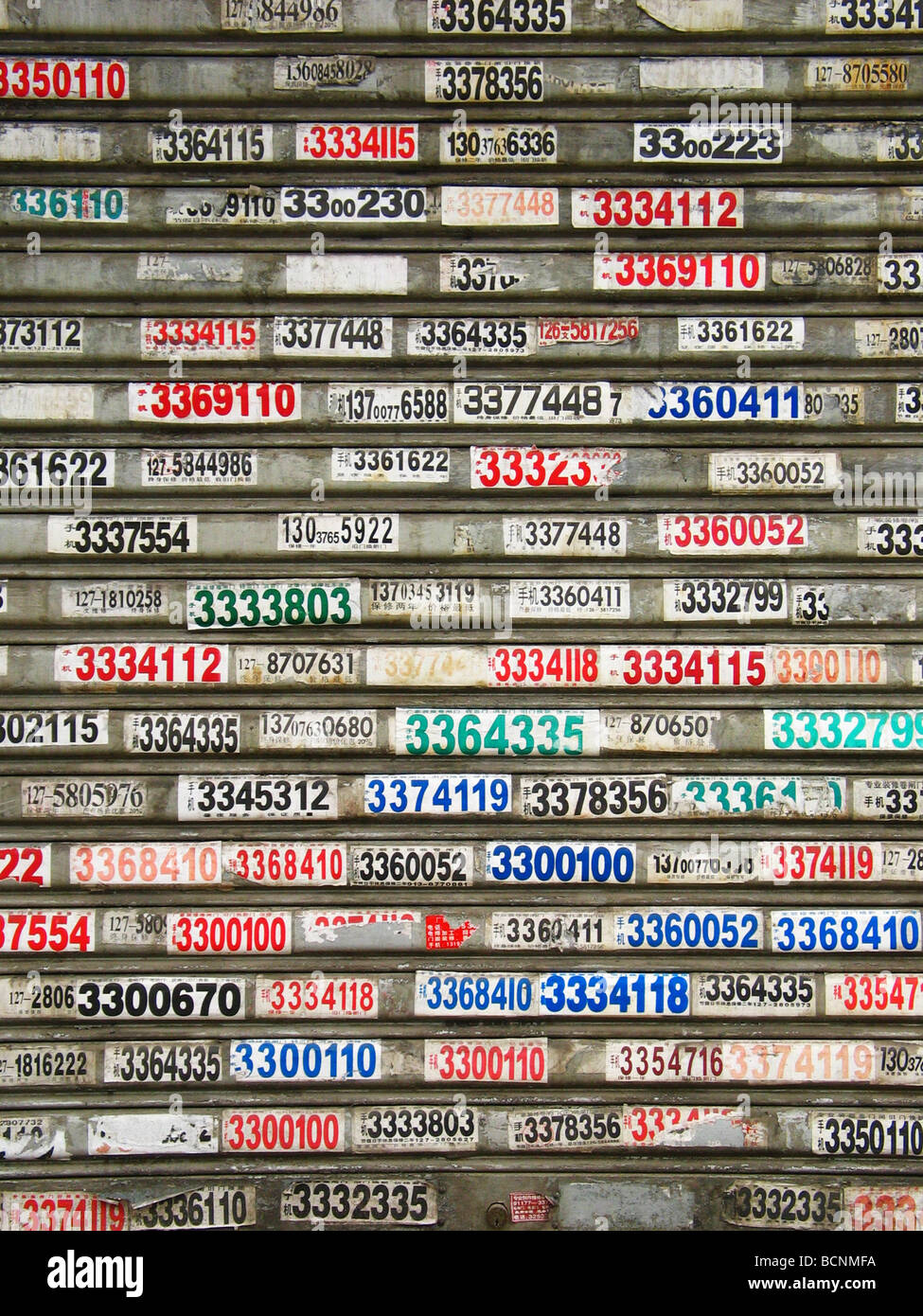 Schichten von Telefon-Nummern-Aufkleber auf Fenstervorhänge von einem lokalen Speicher als Werbung für Arbeitserlaubnis Service, Henan Stockfoto
