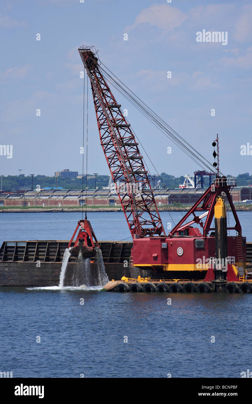 Kran mit einem Clam Shell Eimer auf einem Lastkahn Baggerarbeiten von Hafen von New York. Stockfoto
