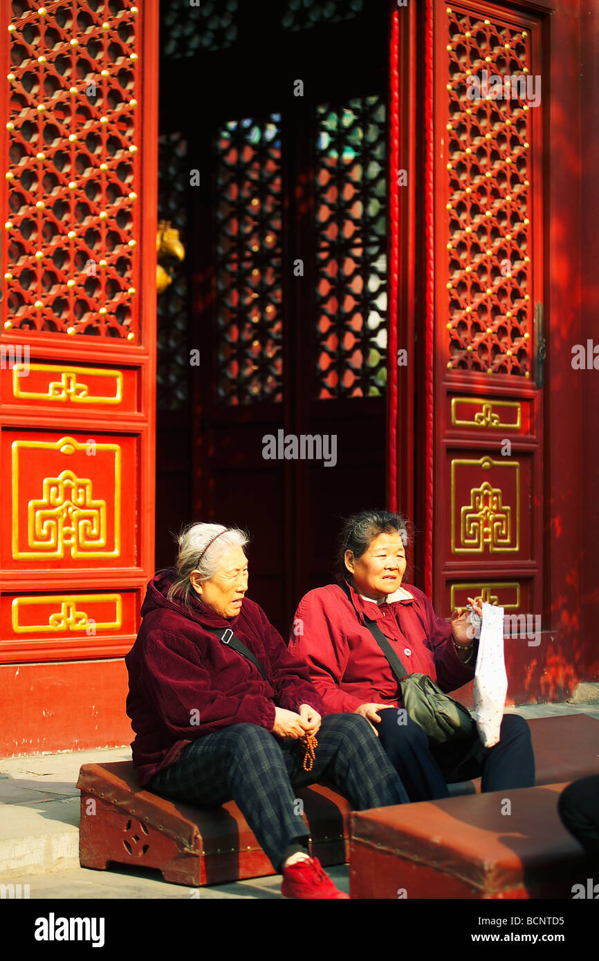 Zwei ältere chinesische Frauen ruht auf Gebetsteppich vor eine große Halle, Fayuan Tempel, Peking, China Stockfoto