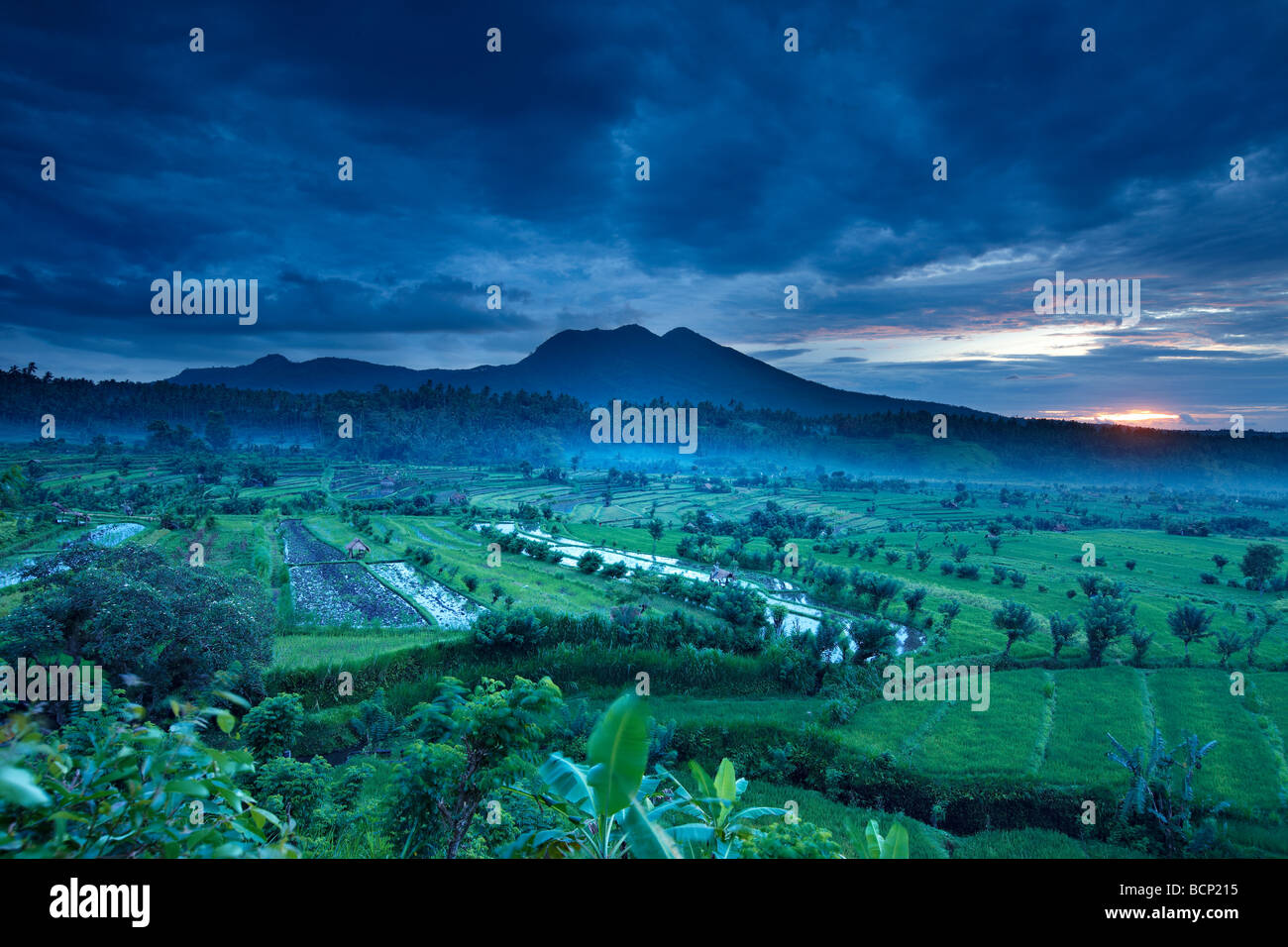 terrassierte Reisfelder in der Nähe von Tirtagangga im Morgengrauen mit der Sonne steigt über die vulkanische Gipfel des Gunung Lempuyang, Bali, Indonesien Stockfoto