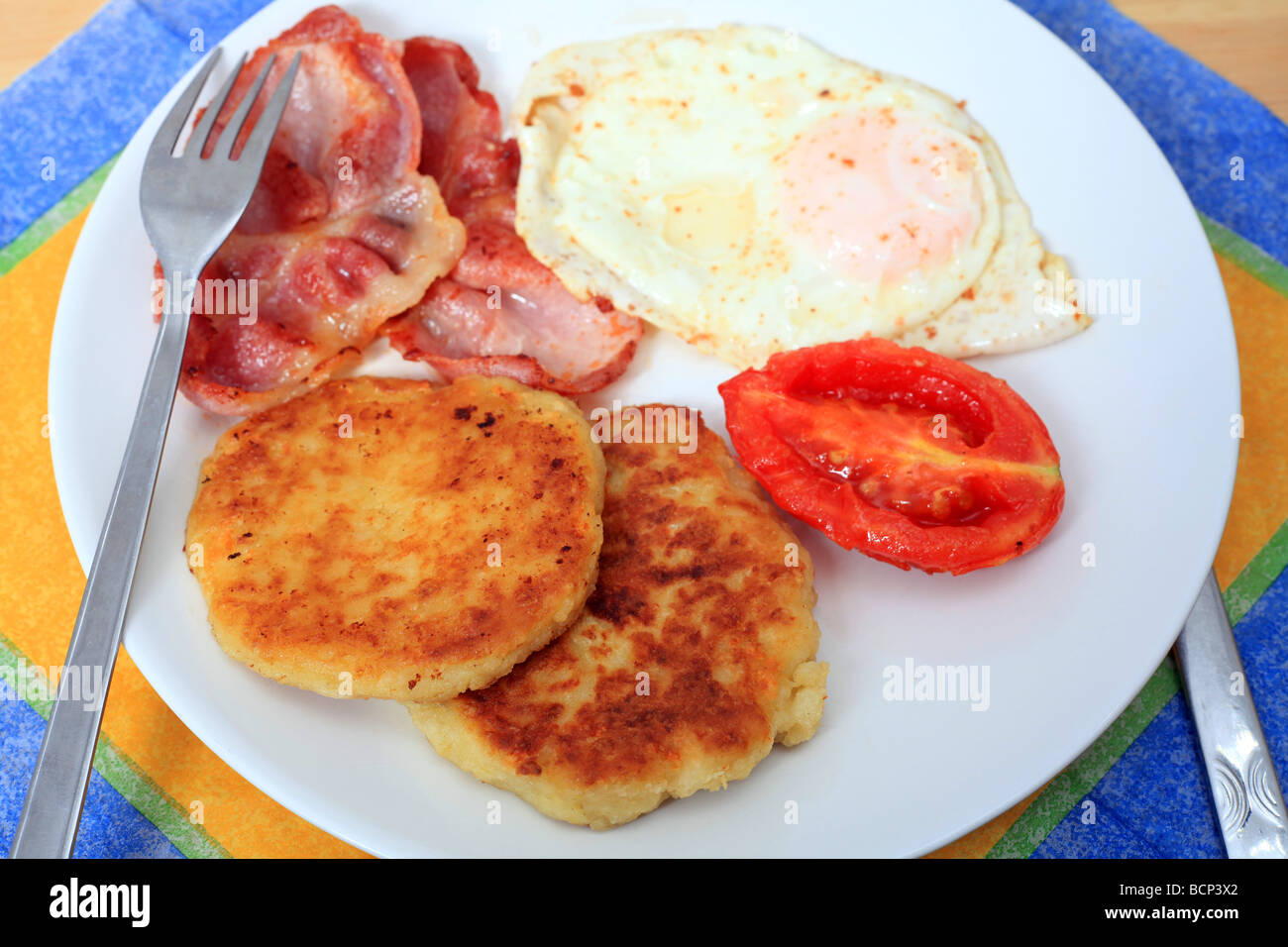 Ein gebratenes Frühstück mit Kartoffel Pfannkuchen, Speck Ei und Tomate Stockfoto
