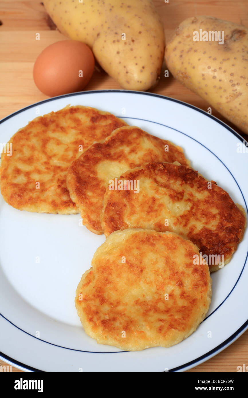 Ein Teller mit frischen gebratenen Kartoffelpfannkuchen mit Kartoffeln und Ei im Hintergrund Stockfoto