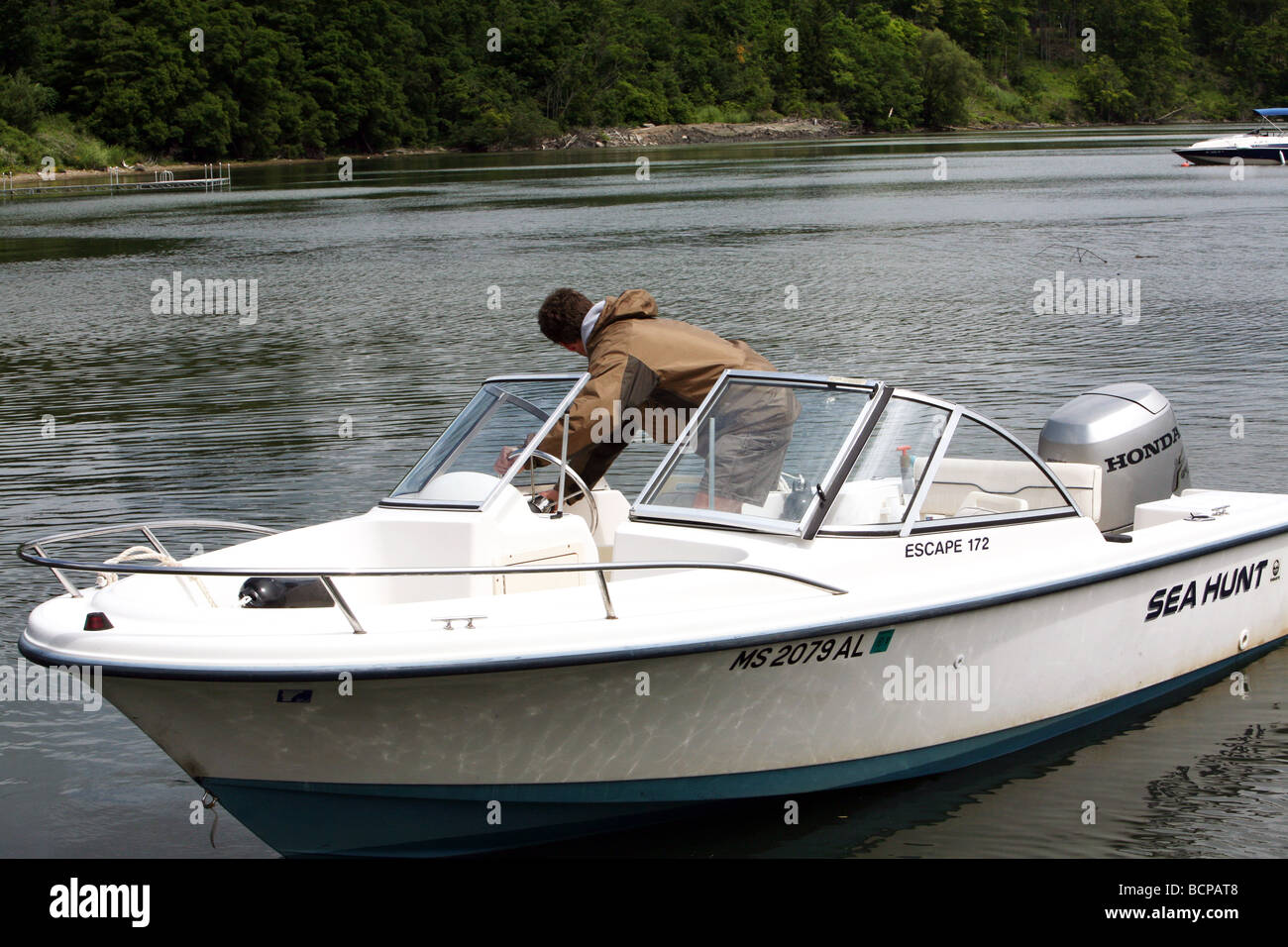 Ein junger Mann seine 17 Fuß Runabout Motorboot herausnehmen. Die Szene ist Lake Champlain mit den Green Mountains von Vermont. Stockfoto