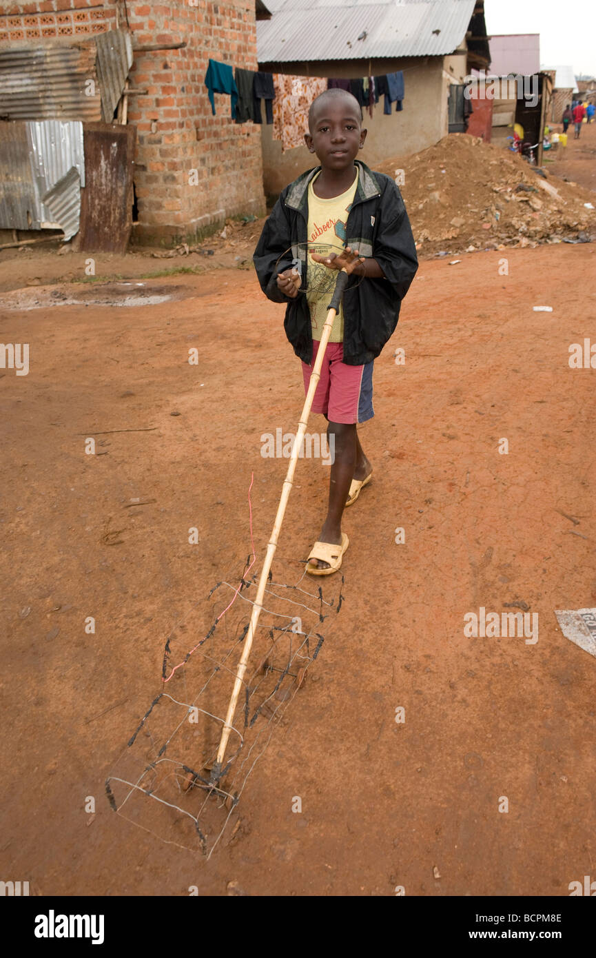 Afrikanischen jungen spielen mit handgefertigten Modellauto auf Kampala Slum Straße Stockfoto