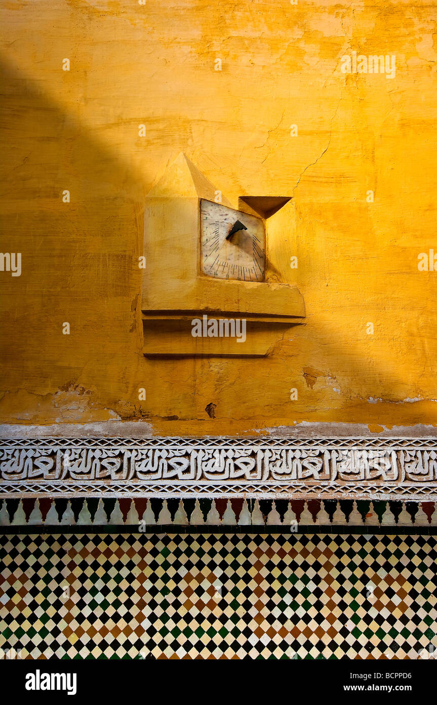 Gelbe Wand im Grab des Moulay Ismail, Meknès, Marokko zeigt eine alte Sonnenuhr und aufwendige Fliesenarbeiten Stockfoto