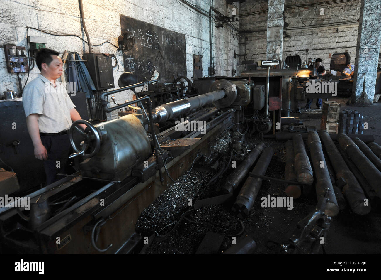 Techniker arbeiten neben Drehmaschine in alten Stein Fabrikraum, Baujahr 1937, Dongfeng Electric Machinery Works Company, Leshan Stockfoto