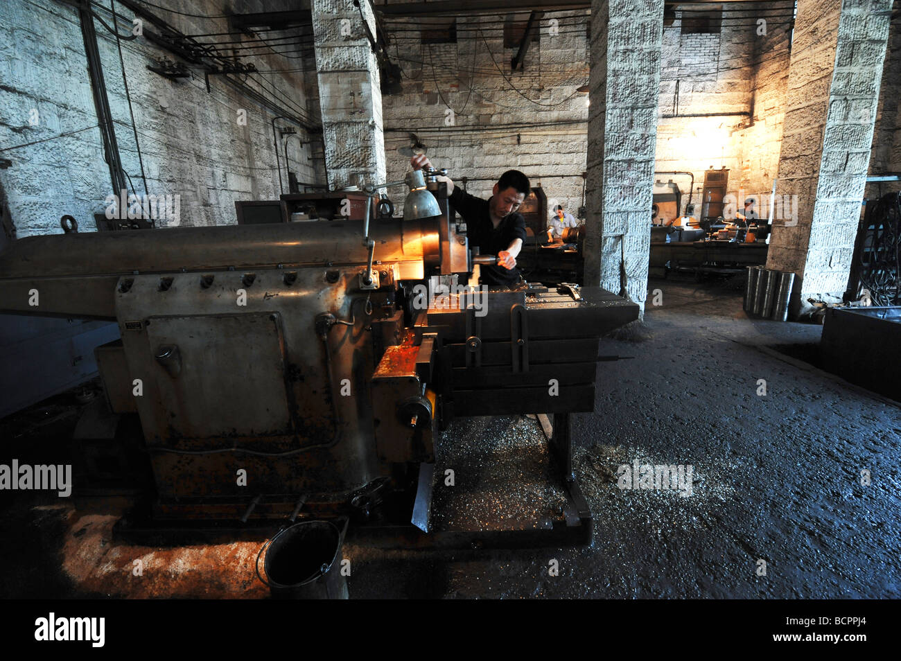 Techniker arbeiten neben Drehmaschine in alten Stein Fabrikraum, Baujahr 1937, Dongfeng Electric Machinery Works Company, Leshan Stockfoto