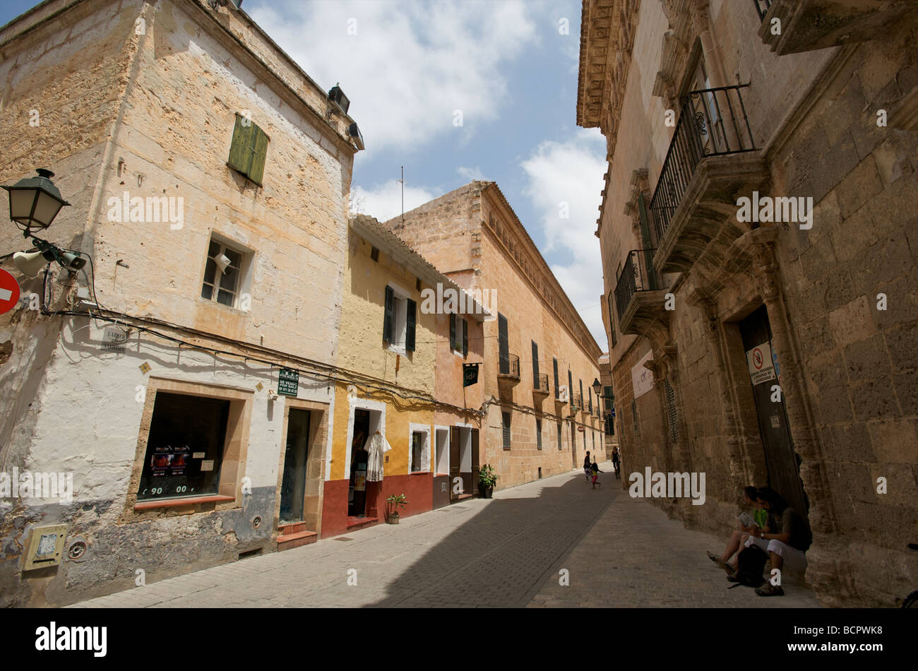 Touristen sitzen im Schatten einer Kirche in Ciutadella Menorca Stockfoto