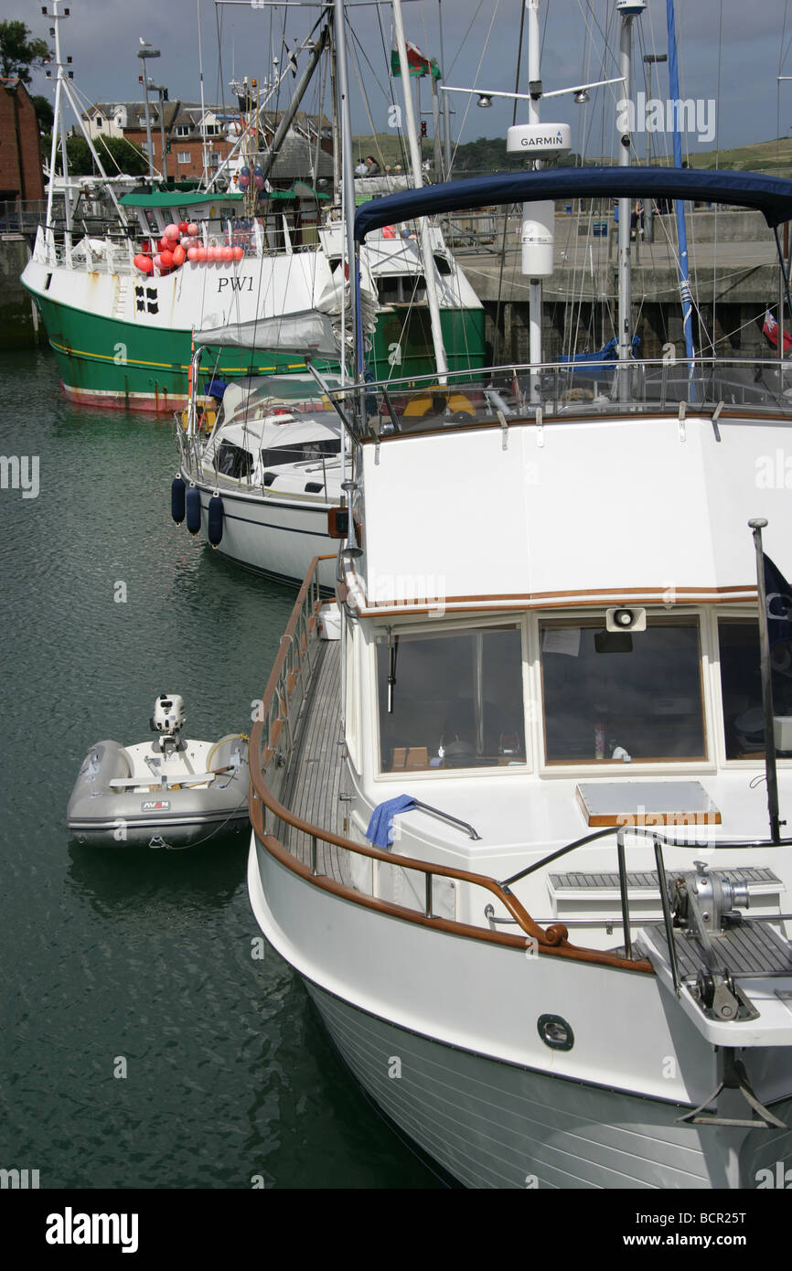 Stadt von Padstow, England. Luxus-Freizeit-Boot vertäut im Hafen von Padstow mit Fischereifahrzeug im Hintergrund. Stockfoto