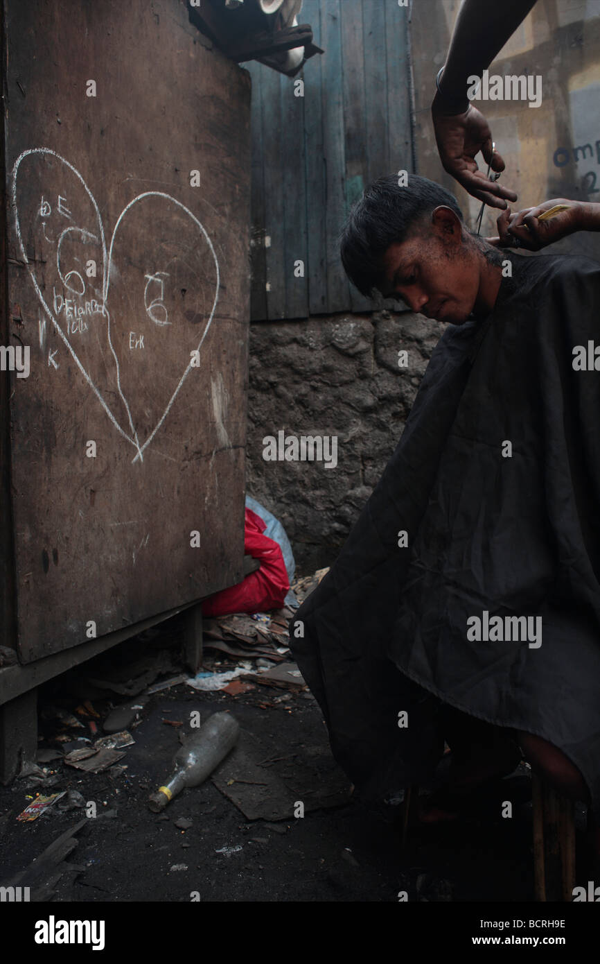 Ein Teenager bekommt seine Frisur in den Slums von Tamabakan, Tondo Bezirk, Philippinen Stockfoto