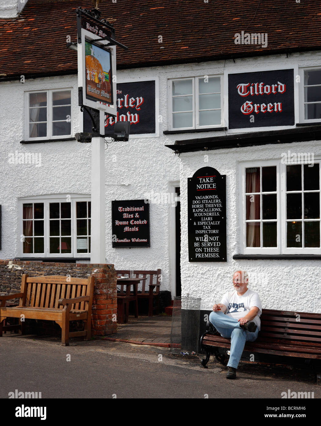 Ein Mann einen Drink außerhalb der Gerste Mähen Gastwirtschaft, Tilford, Farnham, Surrey, England, UK. Stockfoto