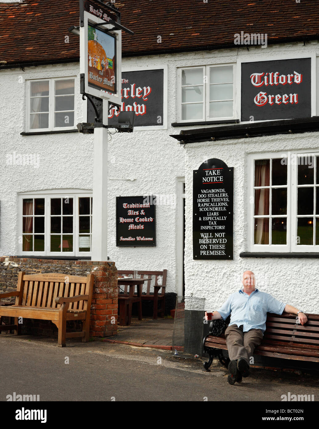 Ein Mann einen Drink außerhalb der Gerste Mähen Gastwirtschaft, Tilford, Farnham, Surrey, England, UK. Stockfoto