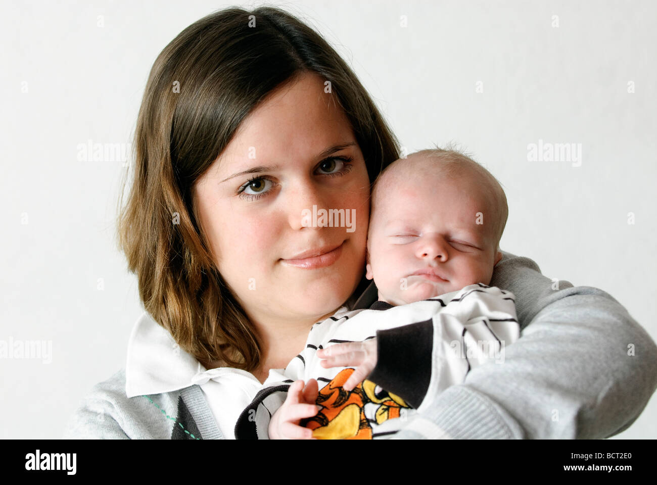 neunzehn Jahre alte Mutter hält ihr Baby Boy auf weißem Hintergrund Stockfoto