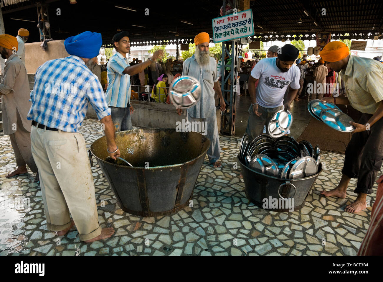 Sikh-Männer waschen in der Gemeinschaftsküche nachdem Pilger eine kostenlose Mahlzeit gegessen. Goldene Tempel (Sri Harmandir Sahib) Amritsar. Indien Stockfoto