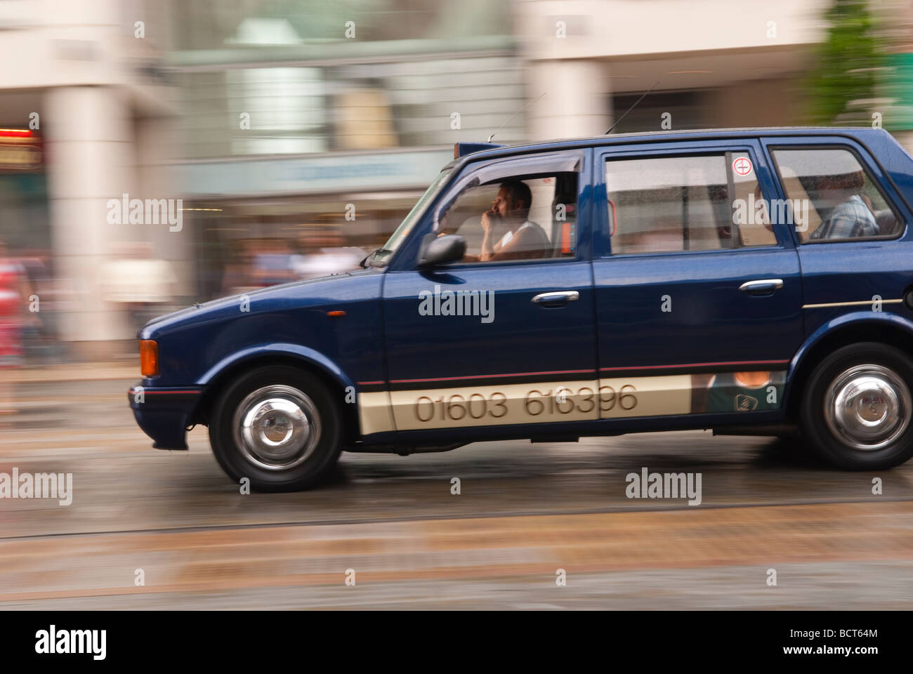 Ein Taxi fährt durch die Innenstadt in den Regen, die Bewegung in Norwich Norfolk Uk Stockfoto