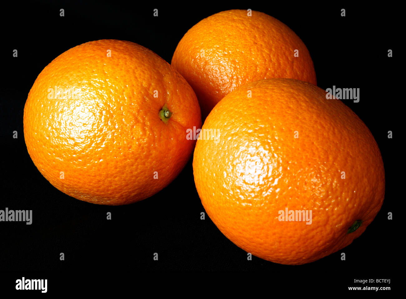 Drei Orangen platziert vor schwarzem Hintergrund Stockfoto