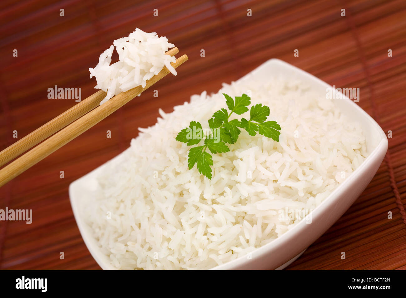 Nahaufnahme von Reis auf Stäbchen und eine Schale auf Matte Stockfoto