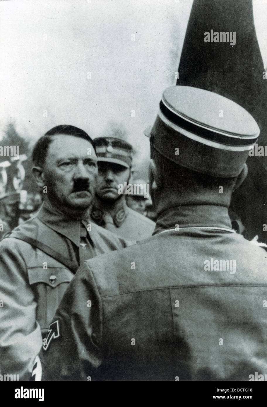 Adolf Hitler "weihen" neue Fahnen mit der Blutfahne Blut Flagge hinter ihm Stabschef Viktor Lutze, historisches Foto b Stockfoto
