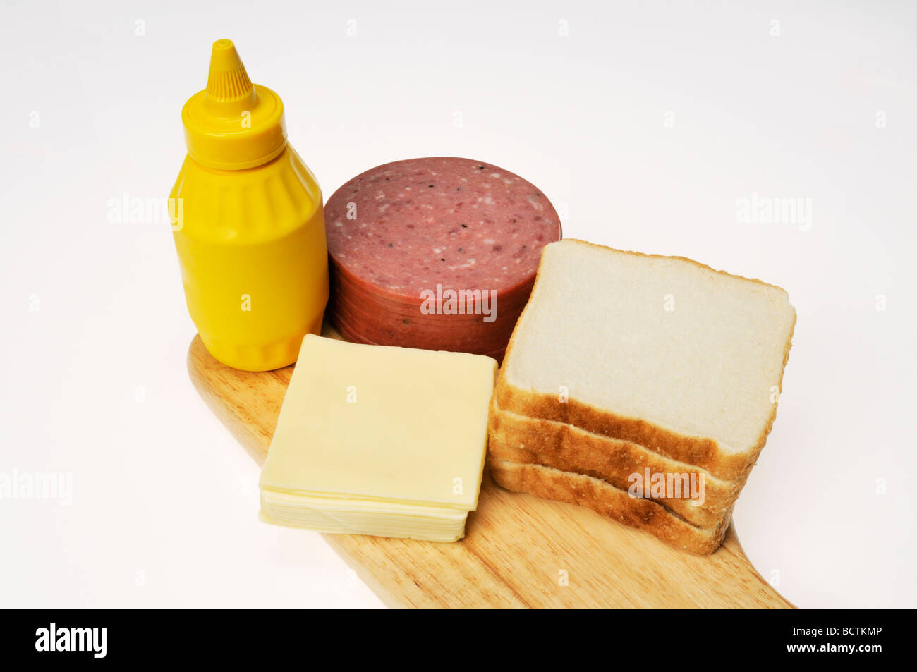 Zutaten für eine Salami und Käse Wurstwaren Sandwich auf weißem Brot mit Senf Stockfoto