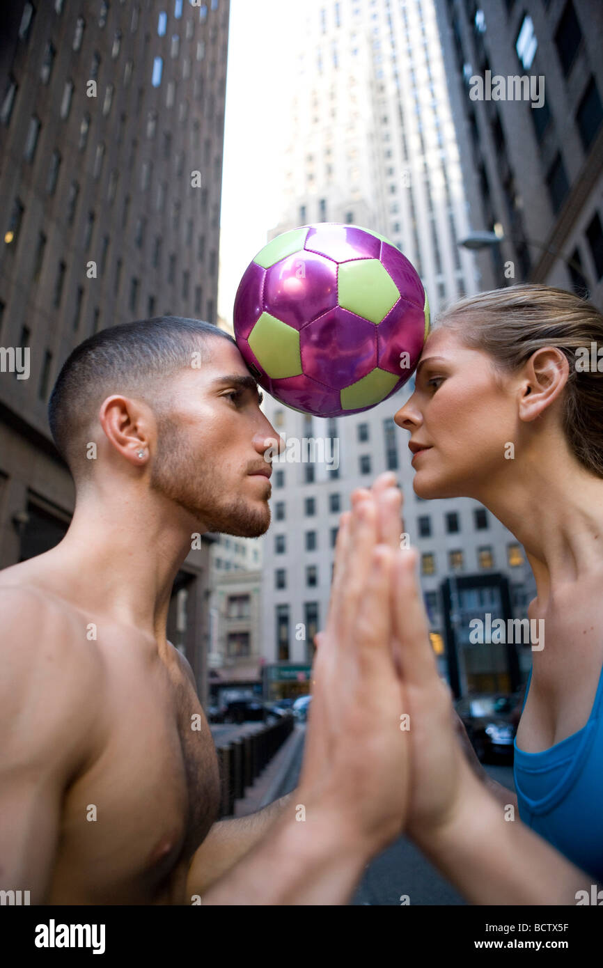 Seitenansicht einer jungen Frau und ein junger Mann mit einem Fußball zwischen ihren Köpfen Stockfoto