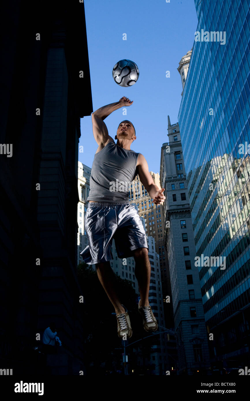 Niedrigen Winkel Blick eines jungen Mannes mit einem Fußball spielen Stockfoto