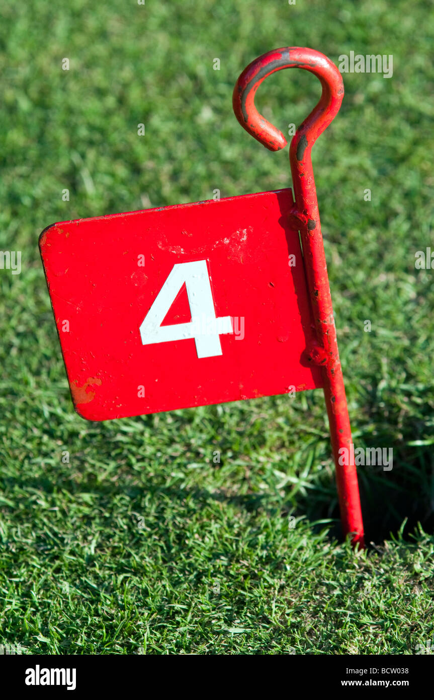 Rote Nummer 4 Metall Minigolf Pflock im Loch auf einer Grünfläche Stockfoto
