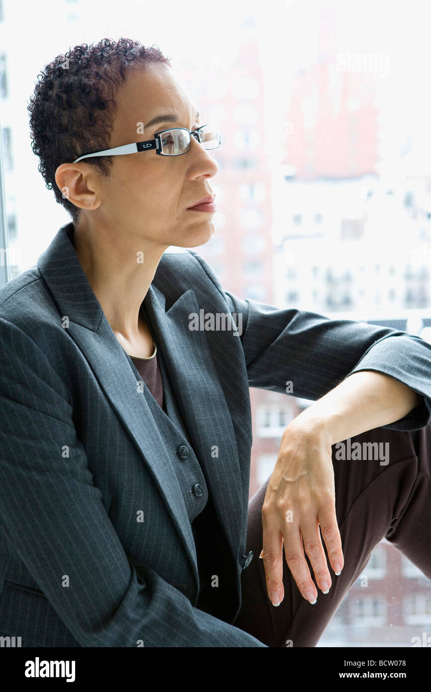 Geschäftsfrau, die mit der Hand auf ihrem Knie sitzt Stockfoto