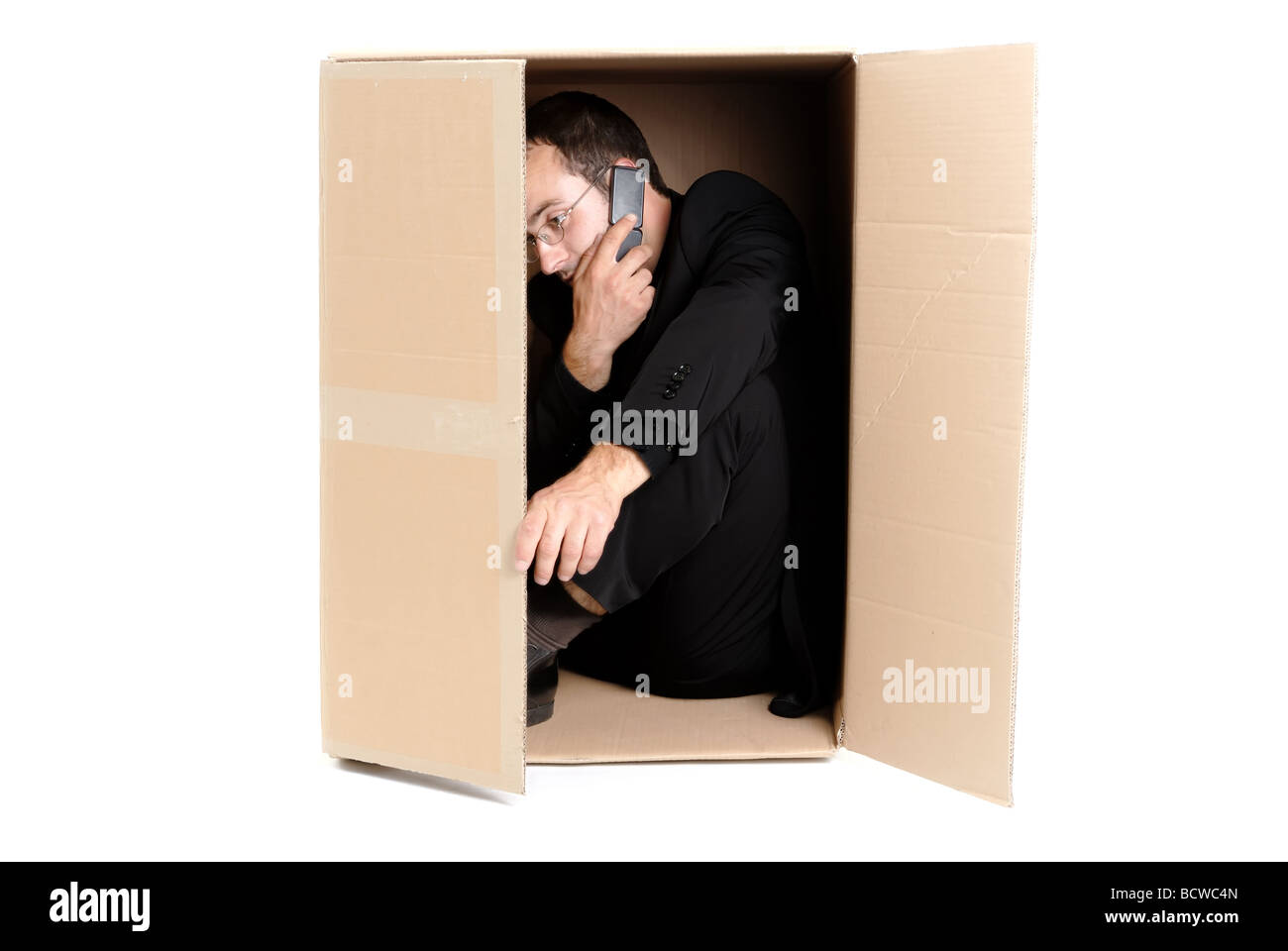 junger Geschäftsmann versteckt und Telefonieren in einem Karton Stockfoto