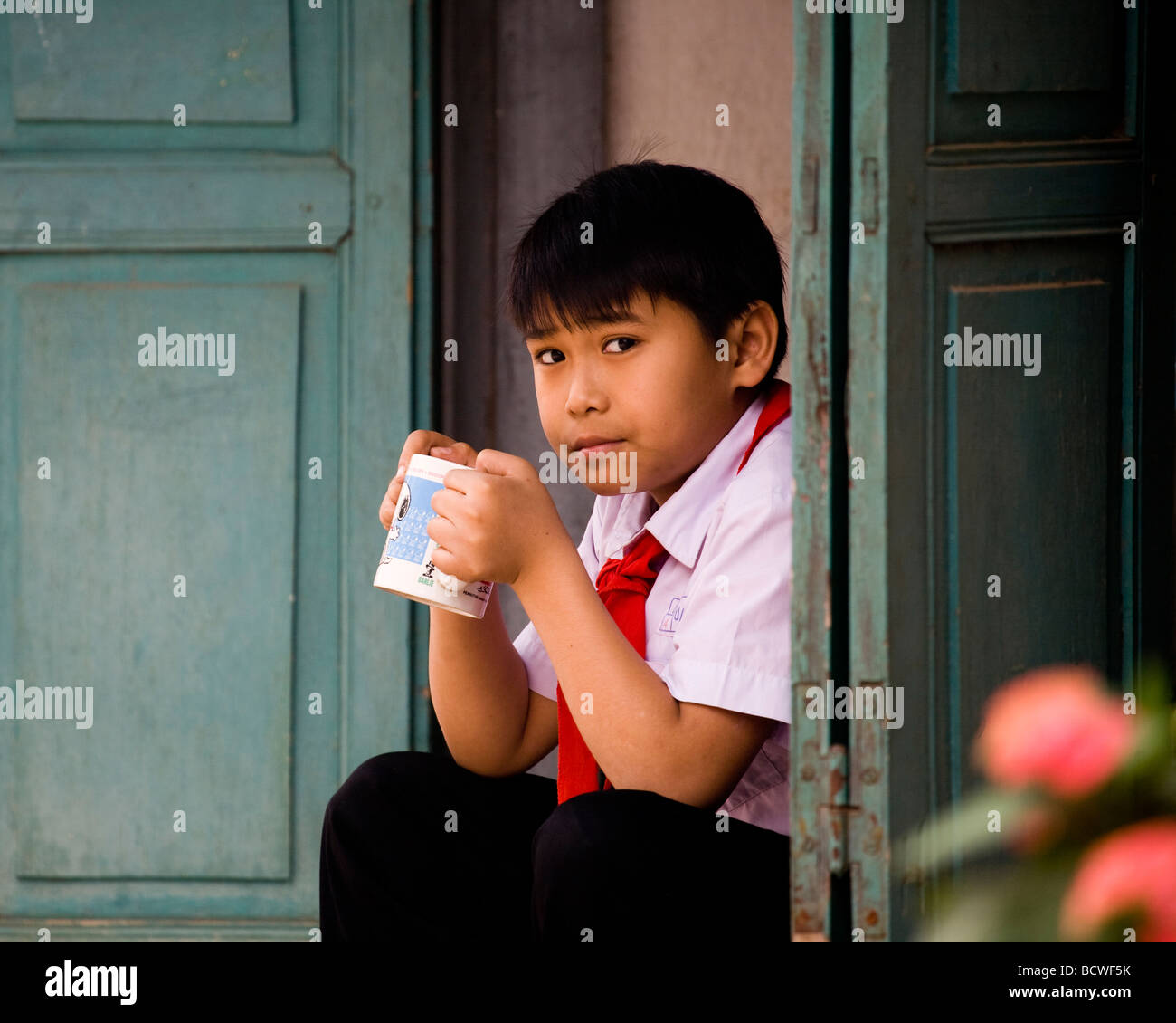 Ein kleiner Junge trinkt Tee in Tür, Luang Prabang, Laos Stockfoto