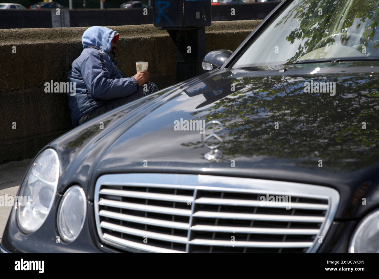 Mann Straße Bettler neben einem Parkscheinautomaten und Mercedes Car auf der Suche nach Kleingeld Dublin City illustrieren Reichtum Ungleichheit liegen Stockfoto