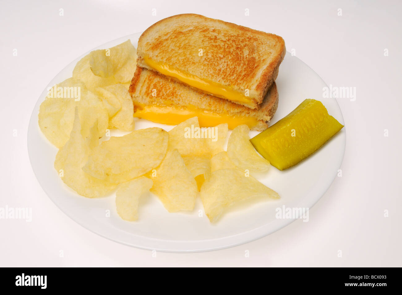 Gegrilltes Käse-Sandwich auf Weißbrot mit Kartoffelchips und Gurke auf weißem Hintergrund Stockfoto